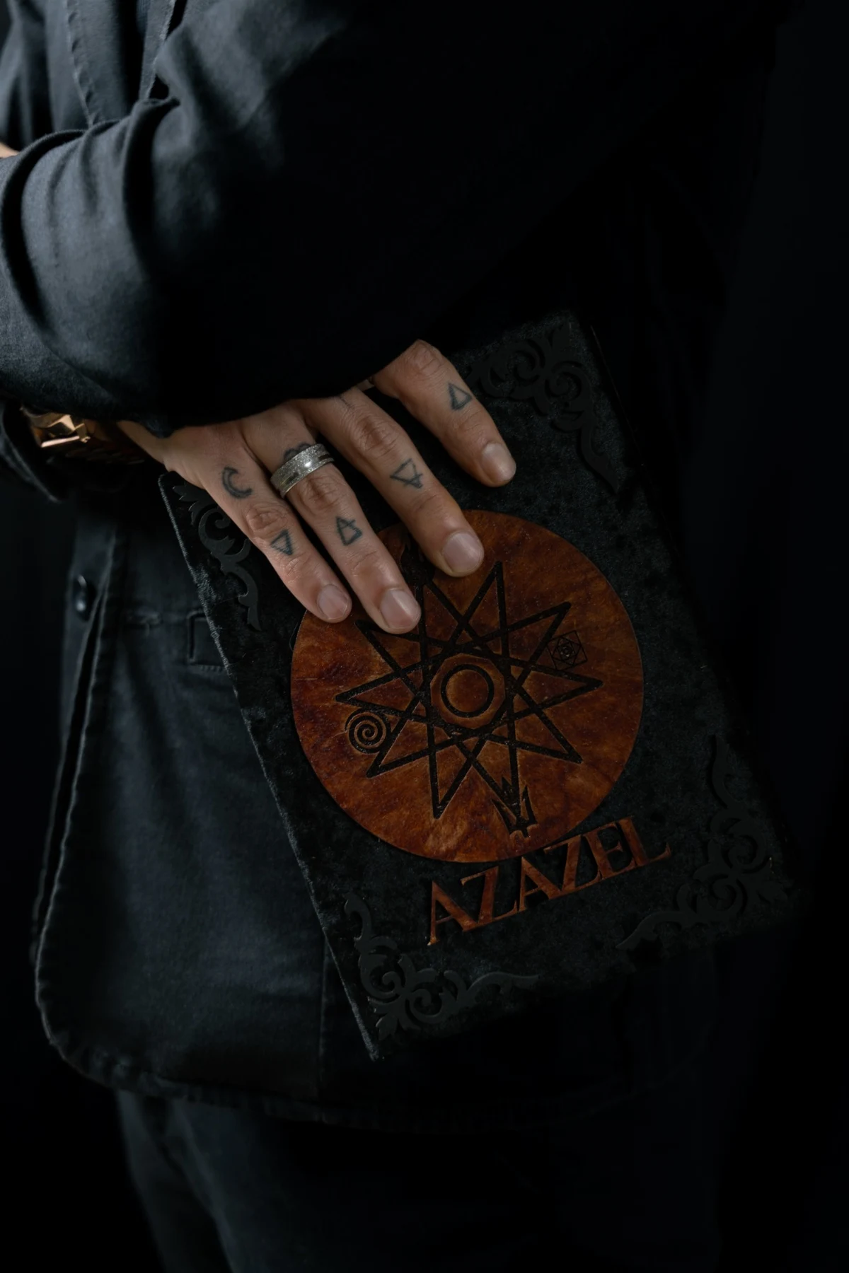 Detalhe do grimório nas mãos de Azazel Qayin